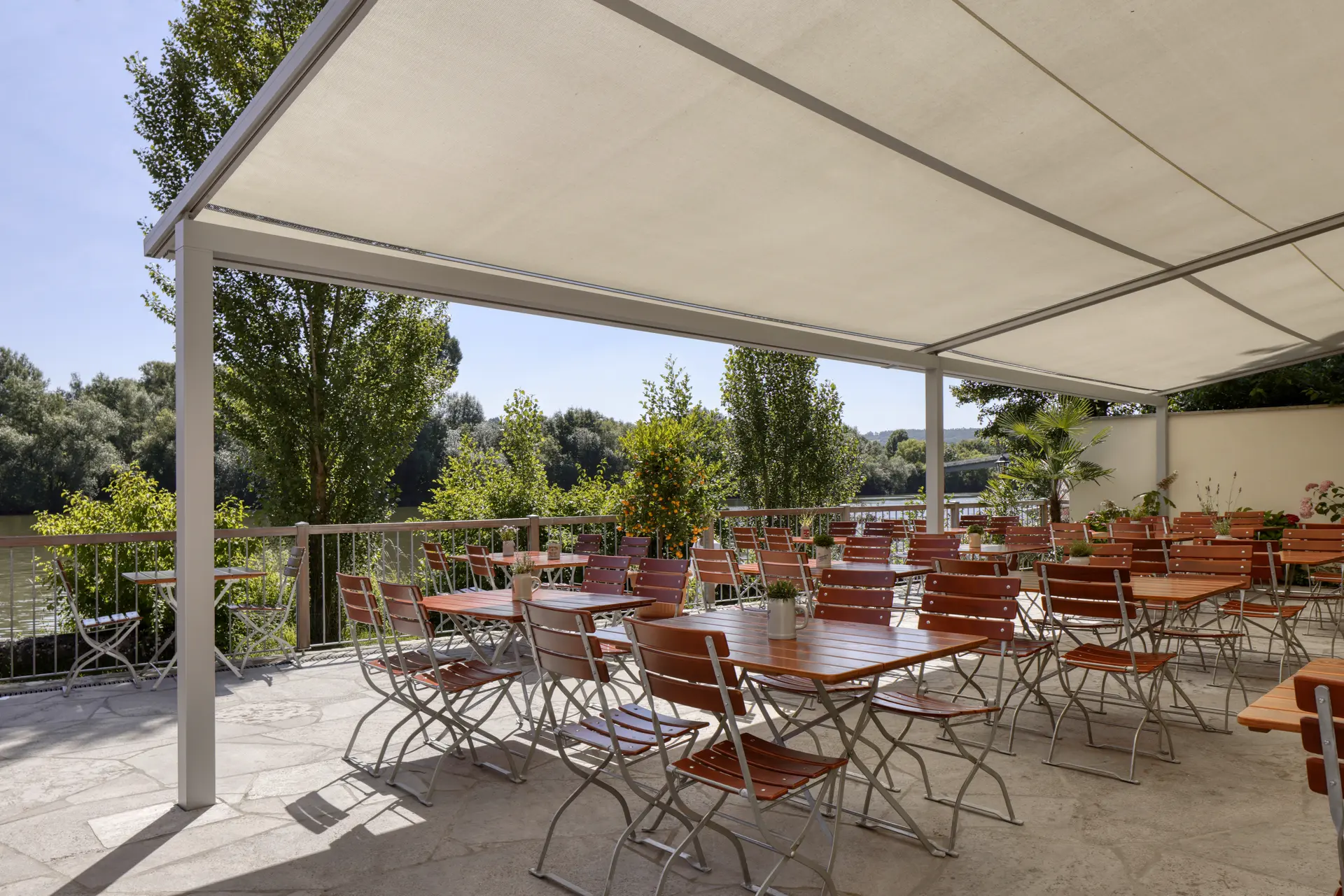 Pergola Markise für die Terrasse Pergola-Markise über einem Außenbereich eines Restaurants mit mehreren Holzstühlen und Tischen